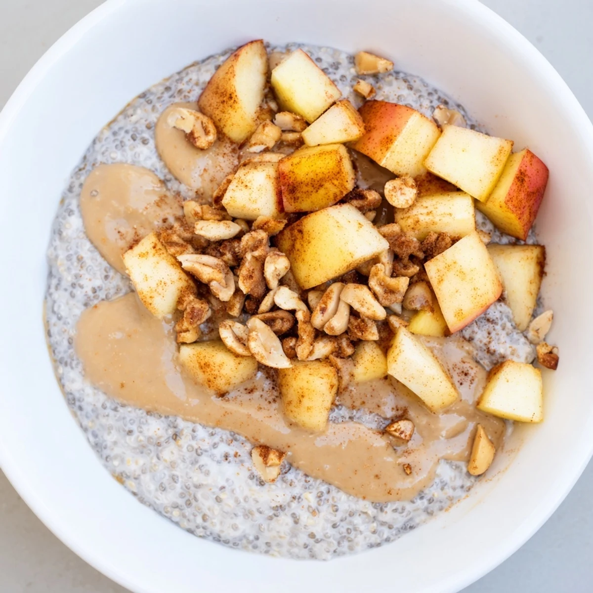 Creamy Apple-Chia Pudding with peanut butter swirls, topped fresh apple slices and chopped peanuts.