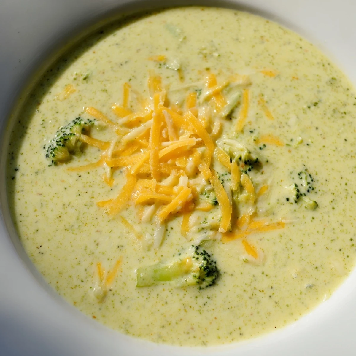 A close-up of creamy Broccoli Cheese Soup, garnished and ready to serve with crusty bread.