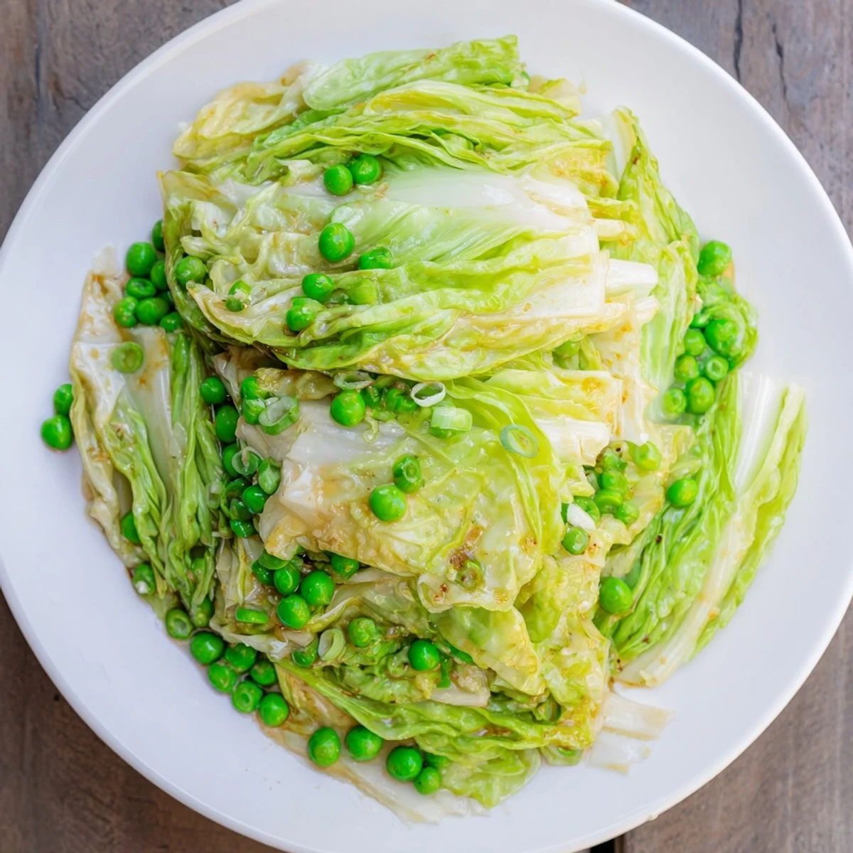 Steaming cabbage stir-fry with peas and a savory sauce glistens, a quick and easy vegetarian dish.