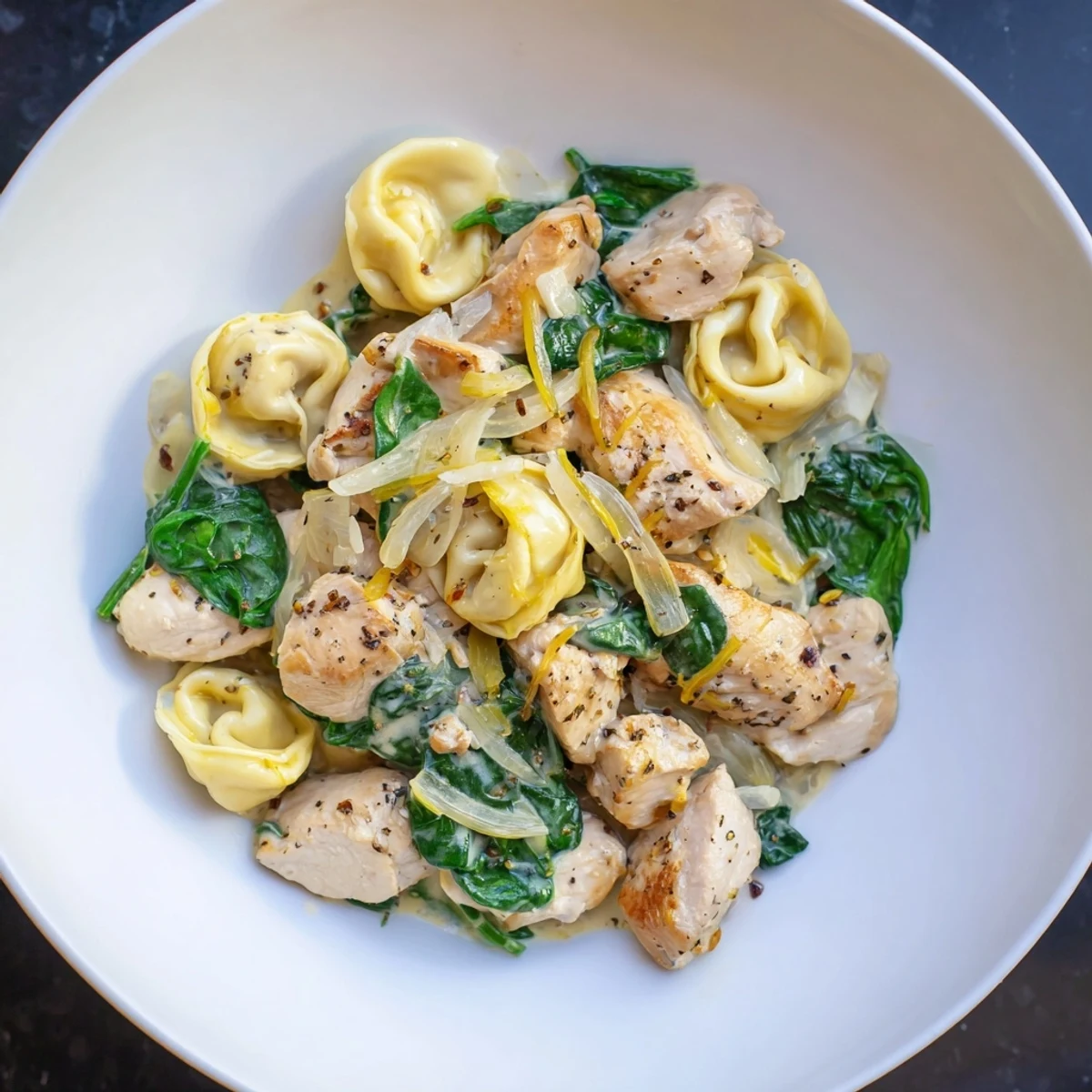 Enjoy a steaming bowl of Creamy Chicken and Spinach Tortellini, with vibrant green spinach and golden chicken.