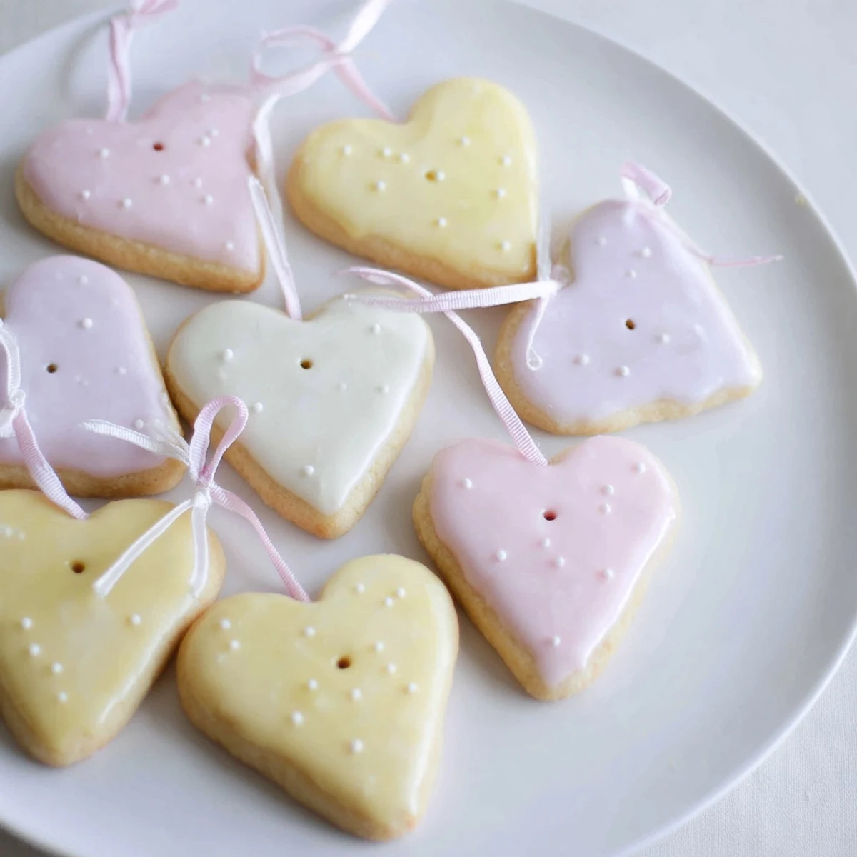 Close-up of golden-baked Mignonneries Coeurs et Étoiles cookies, drizzled with icing, perfect for a gift.