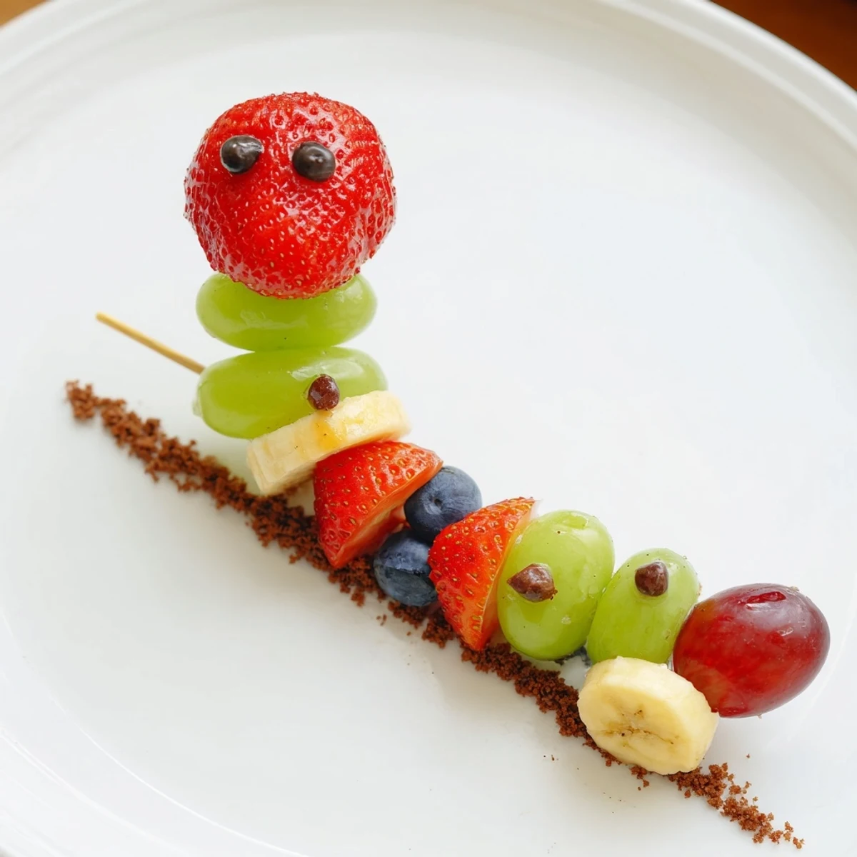 Detailed Caterpillar Fruit Skewer Track: Sweet strawberries and grapes on a chocolate cookie crumb serving trail.