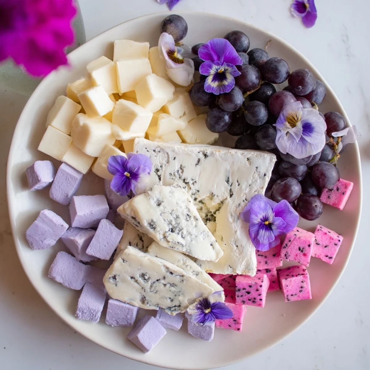Lavender Haze Dreamscape cheese board, piled high with creamy cheeses among colorful fruits and edible flowers.
