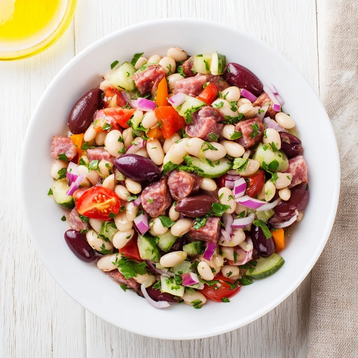 Close-up of a rustic bowl filled with fresh Mediterranean Dense Bean Salad and savory salami.