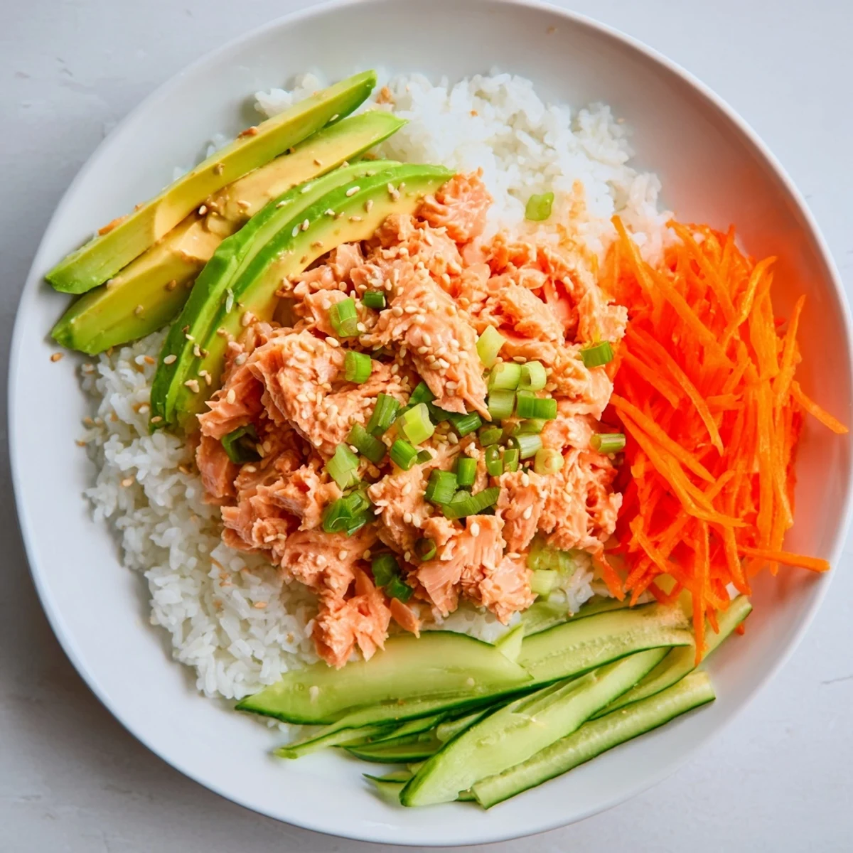 Vibrant Spicy Canned Salmon Rice Bowl, featuring creamy sriracha salmon, served with fresh cucumber.