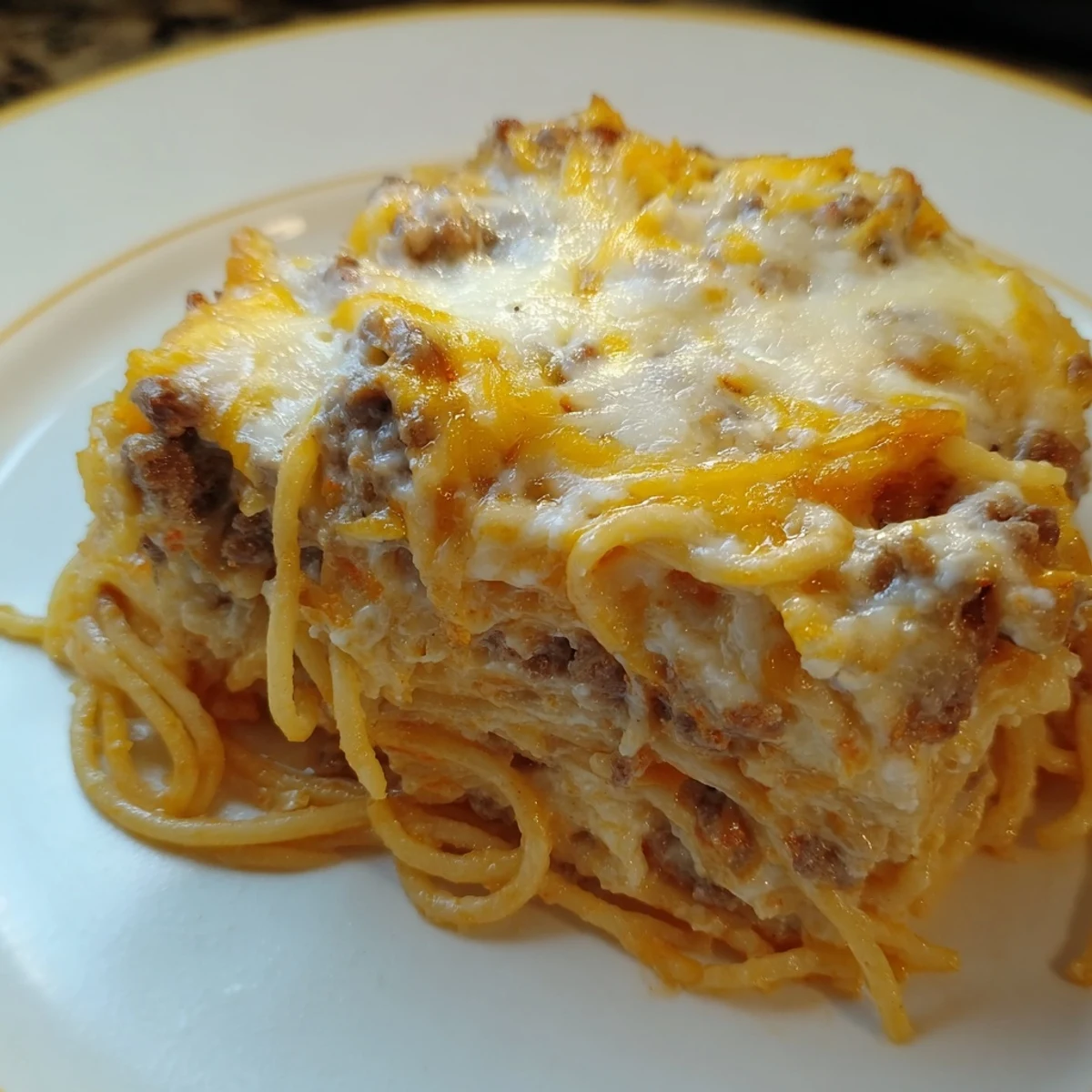 Golden cheesy top on a baking dish filled with richly layered Million Dollar Spaghetti, hearty and delicious.