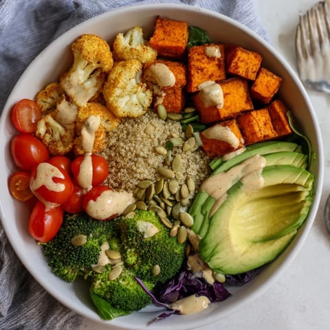 Vibrant Veggie-Packed Buddha Bowl topped with creamy tahini dressing and fresh greens.  