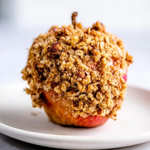 Warm, golden brown baked apples with oat-nut crumble, a comforting fall dessert.