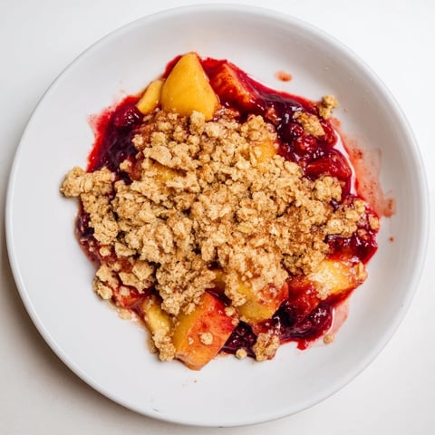 Golden brown fruit crisp with frozen fruit bubbling hot, ready to serve with vanilla ice cream.