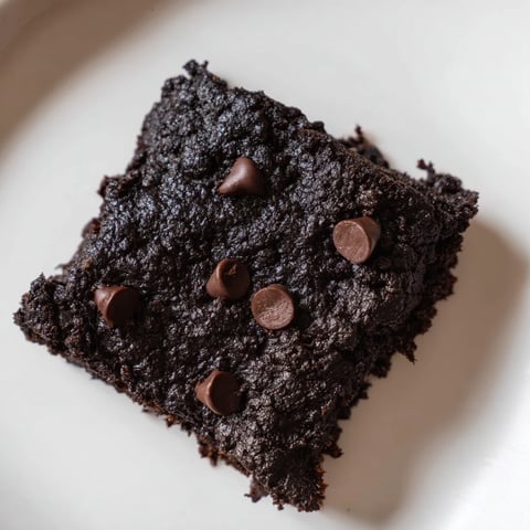 Fudgy, rich Black Bean Brownies ready to eat, with glistening chocolate chips on top.