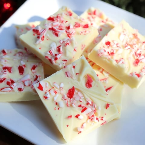 A close-up of creamy, swirled White Chocolate Peppermint Bark Fudge topped with vibrant candy cane pieces.