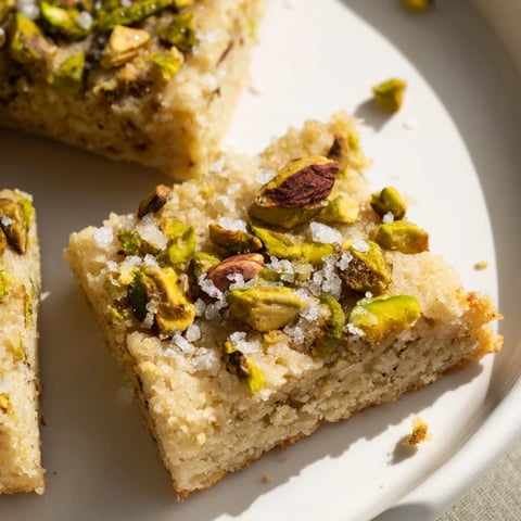 Golden, buttery Salted Pistachio Slice & Bake Shortbread cookies glistening with flaky sea salt, ready to enjoy.
