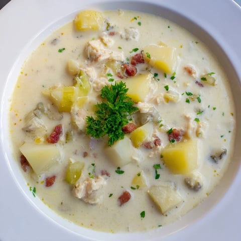 A steaming bowl of creamy New England Clam Chowder, filled with tender clams and potatoes.