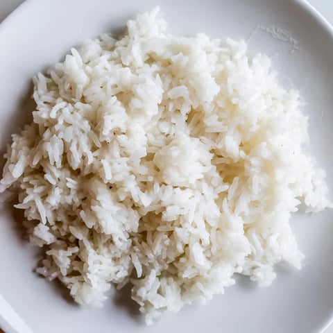 Fluffy Coconut Jasmine Rice, steaming hot, served alongside vibrant green Thai curry.