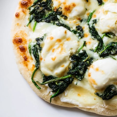 Golden spinach ricotta pizza baked on a thin crust, featuring creamy ricotta, sautéed spinach, and melted mozzarella for a vegetarian main dish.
