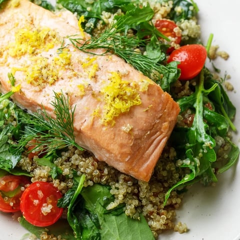 Flaky baked salmon rests atop a vibrant quinoa and herb salad, dressed with a zesty lemon vinaigrette.