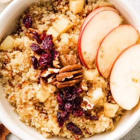 Steaming Apple Cinnamon Quinoa Bowl, a healthy breakfast topped with crunchy walnuts and sweet raisins.