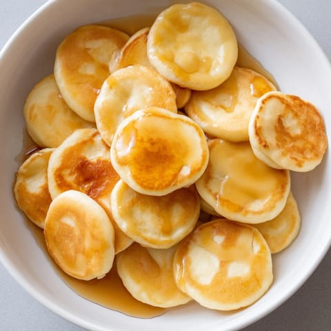 Miniature fluffy pancake cereal, ready to be eaten, perfect for a cozy weekend breakfast.