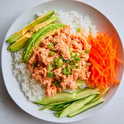 Vibrant Spicy Canned Salmon Rice Bowl, featuring creamy sriracha salmon, served with fresh cucumber.