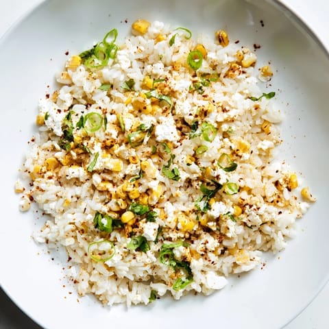 Bright image: creamy Mexican Street Corn Rice with charred corn and crumbled cotija cheese visible.