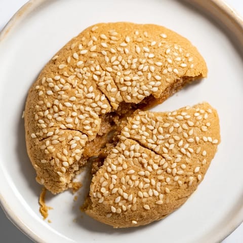 A beautiful close-up of freshly baked and sesame-coated Palestinian Kahk cookies on a tray.