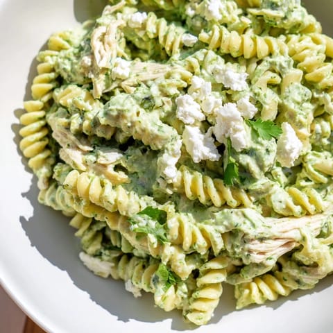 Vibrant bowl of cilantro lime chicken pasta tossed with rotini, creamy green sauce, and crumbled cotija cheese.