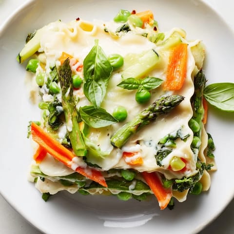 A slice of vegetarian Spring Veggie Alfredo Lasagna on a plate with fresh basil garnish.