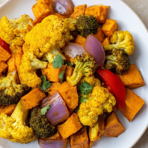 Roasted turmeric vegetables, including red bell pepper and carrots, served warm alongside fluffy quinoa for a nourishing gluten-free meal.