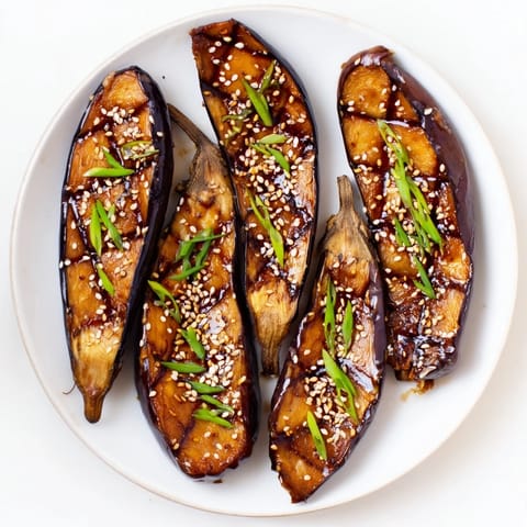 Silky, tender eggplant halves topped with a rich miso glaze, garnished with toasted sesame seeds and fresh green onions.