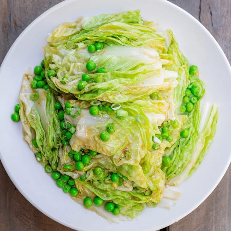 Steaming cabbage stir-fry with peas and a savory sauce glistens, a quick and easy vegetarian dish.