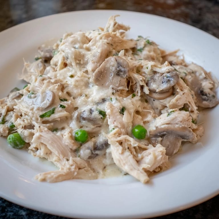 Golden, slow-cooked Creamy Chicken Alfredo, ready to serve over steaming hot pasta for dinner.