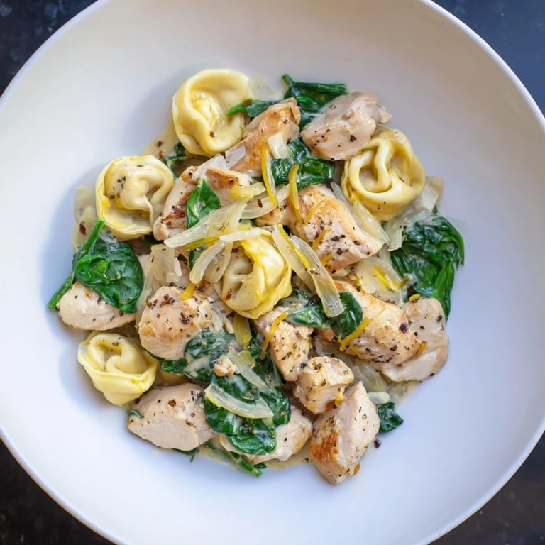 Enjoy a steaming bowl of Creamy Chicken and Spinach Tortellini, with vibrant green spinach and golden chicken.