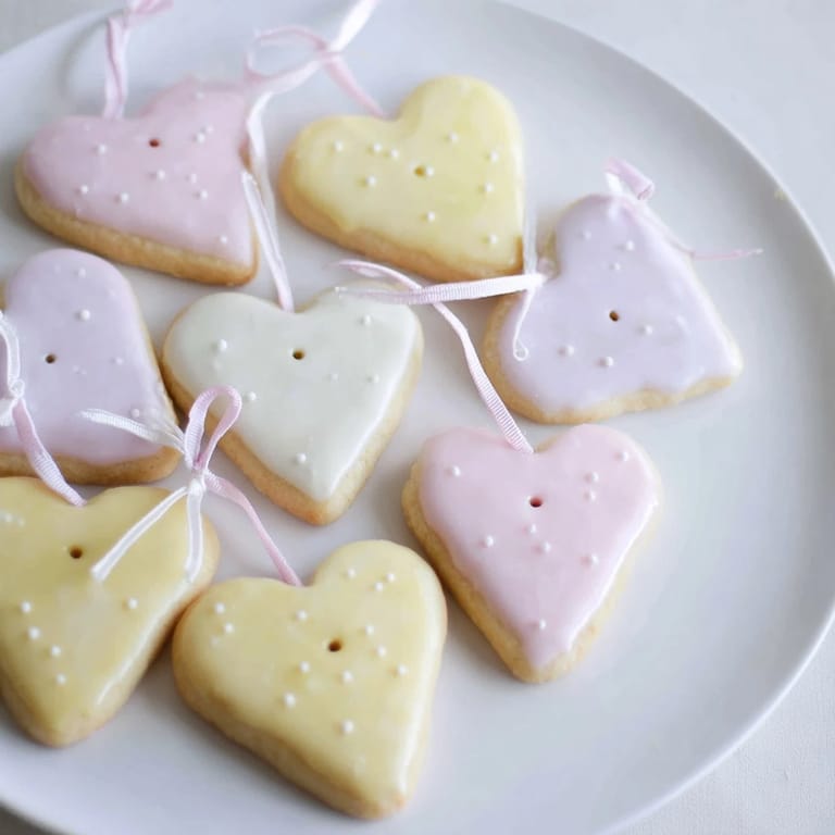Close-up of golden-baked Mignonneries Coeurs et Étoiles cookies, drizzled with icing, perfect for a gift.