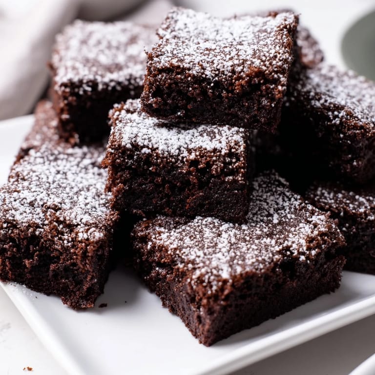 Rich chocolate brownie squares, slightly frosted with powdered sugar, perfect for any sweet craving.