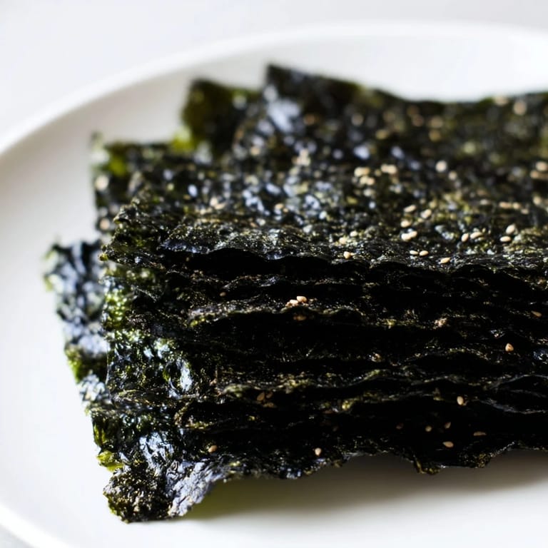 Roasted seaweed chips arranged on parchment paper, golden green and crunchy, perfect for vegan snacking.