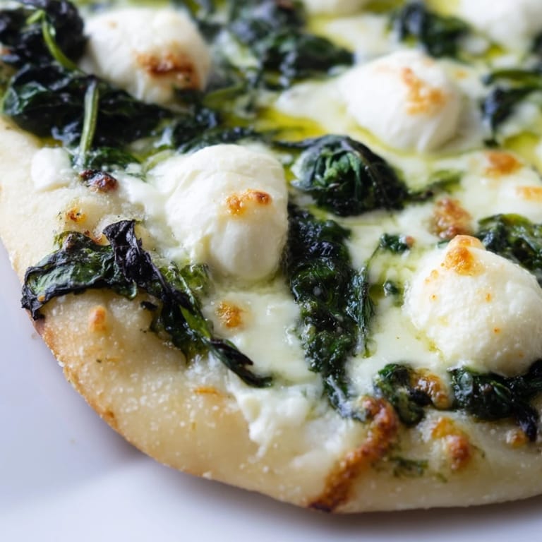 Homemade spinach ricotta pizza with bubbling cheese, sautéed greens, and a golden edge, served on a wooden cutting board for a weeknight vegetarian meal.