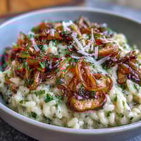 Creamy caramelized onion and mushroom risotto in a skillet, topped with fresh parsley and Parmesan shavings for an elegant vegetarian main dish.