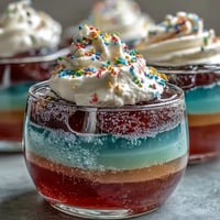 Vibrant Rainbow Jello Cups for Kids, showcasing layered fruity colors and creamy topping.